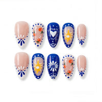 Colorful nail tips featuring orange fruit, flowers, and sun designs on blue and nude nails.
