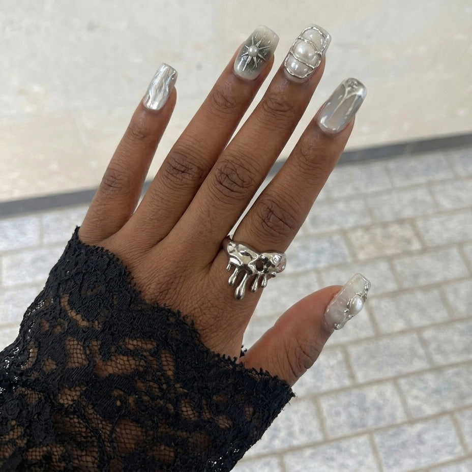 A set of elegant short square nail art designs featuring metallic details, pearls, and glossy finishes in neutral colors.