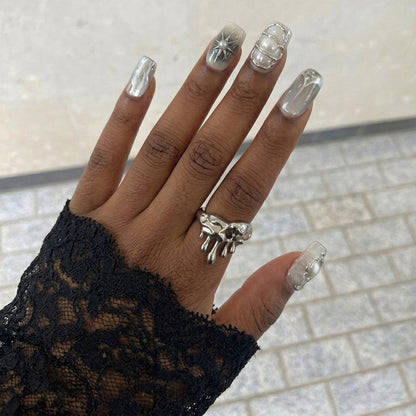 A set of elegant short square nail art designs featuring metallic details, pearls, and glossy finishes in neutral colors.