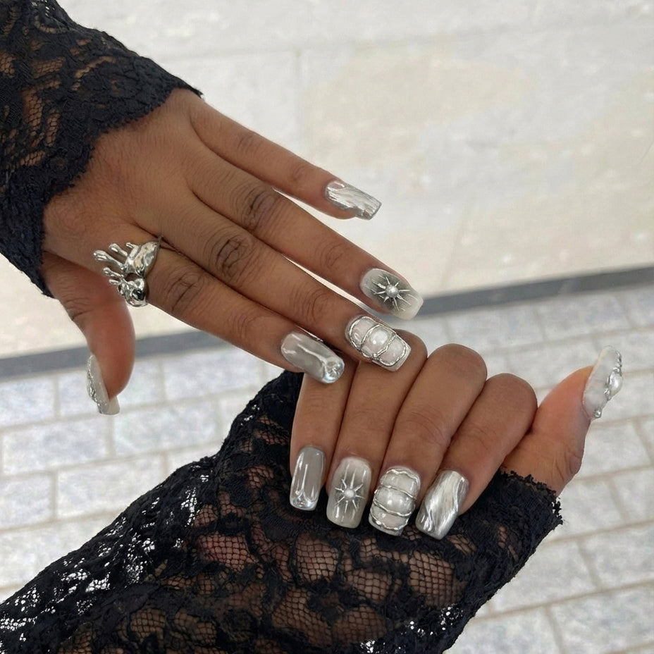 A set of elegant short square nail art designs featuring metallic details, pearls, and glossy finishes in neutral colors.