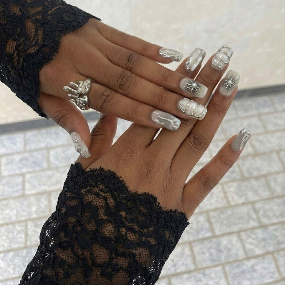 A set of elegant short square nail art designs featuring metallic details, pearls, and glossy finishes in neutral colors.