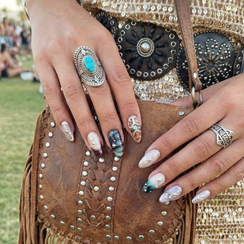 Close-up of hands with stylish nails. Ten colorful nail designs with various patterns and embellishments, including stars and pearls.