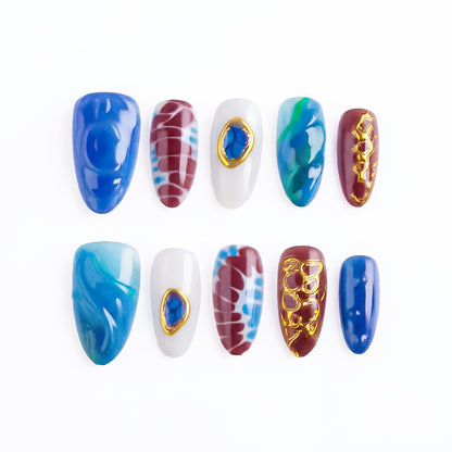 A set of colorful press-on nails with blue, brown, and white designs, some with gold accents.