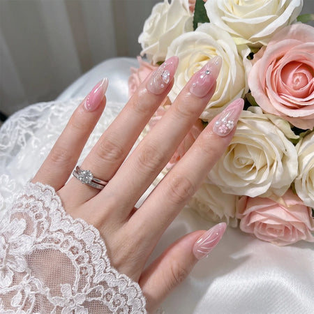Garden of Forever pink ombre bridal nail art with iridescent butterfly, 3D cherry blossom flowers, pearl accents and swirl designs on almond nails, styled with roses and diamond wedding ring