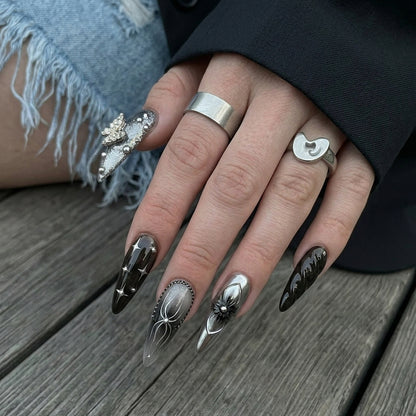Ten stylish stiletto nails in black, gray, and silver shades with various decorations like flowers, chains, and sparkles.