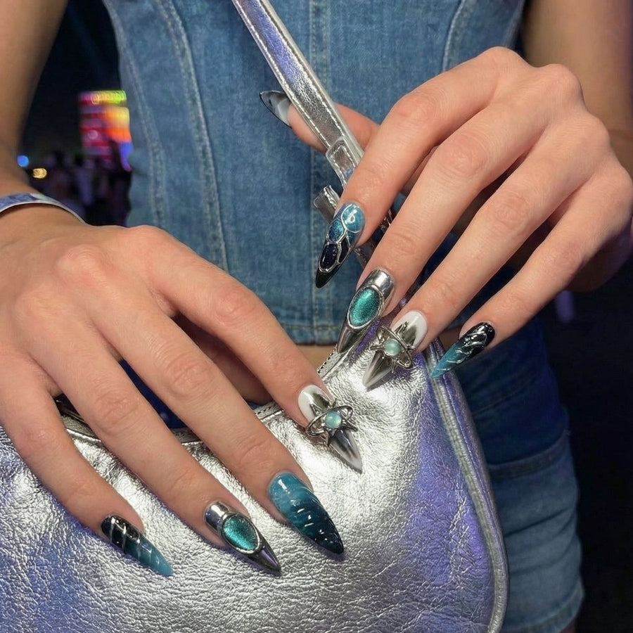 Set of stylish stiletto nails featuring teal and black designs with shiny metallic accents.