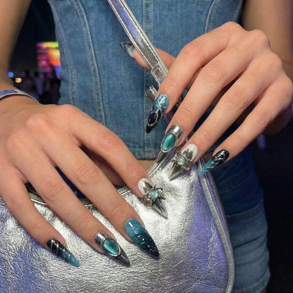 Set of stylish stiletto nails featuring teal and black designs with shiny metallic accents.