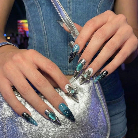 Set of stylish stiletto nails featuring teal and black designs with shiny metallic accents.