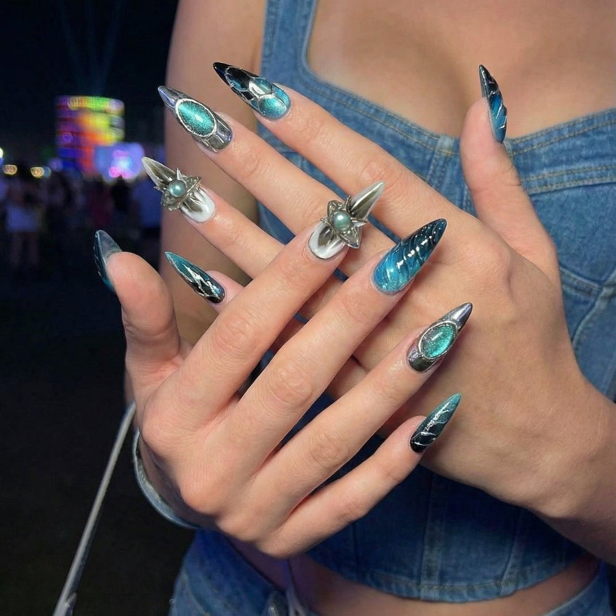 Set of stylish stiletto nails featuring teal and black designs with shiny metallic accents.