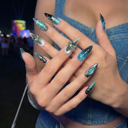 Set of stylish stiletto nails featuring teal and black designs with shiny metallic accents.