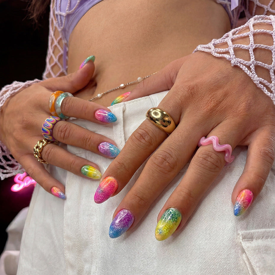 Ten colorful press-on nails in pink, purple, blue, and green shades with glitter.
