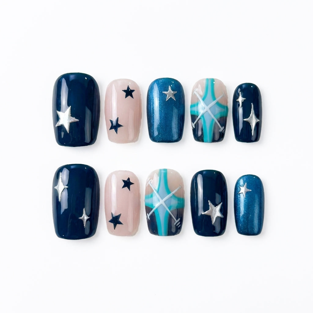Nail art design featuring navy, teal, and nude colors with stars and cross patterns.