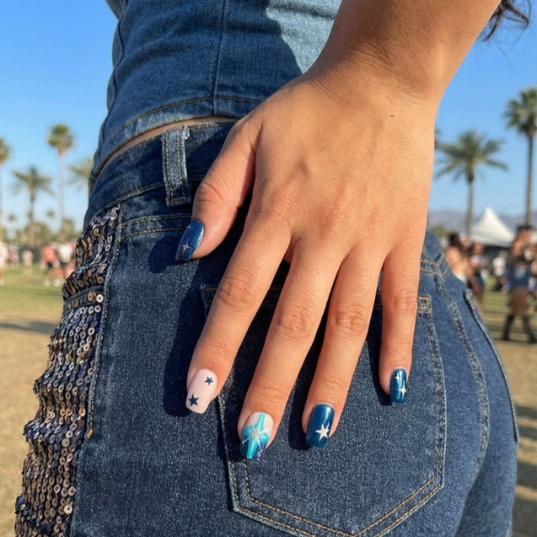 Nail art design featuring navy, teal, and nude colors with stars and cross patterns.