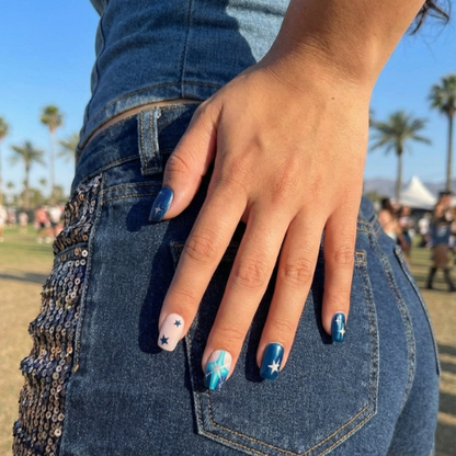 Nail art design featuring navy, teal, and nude colors with stars and cross patterns.