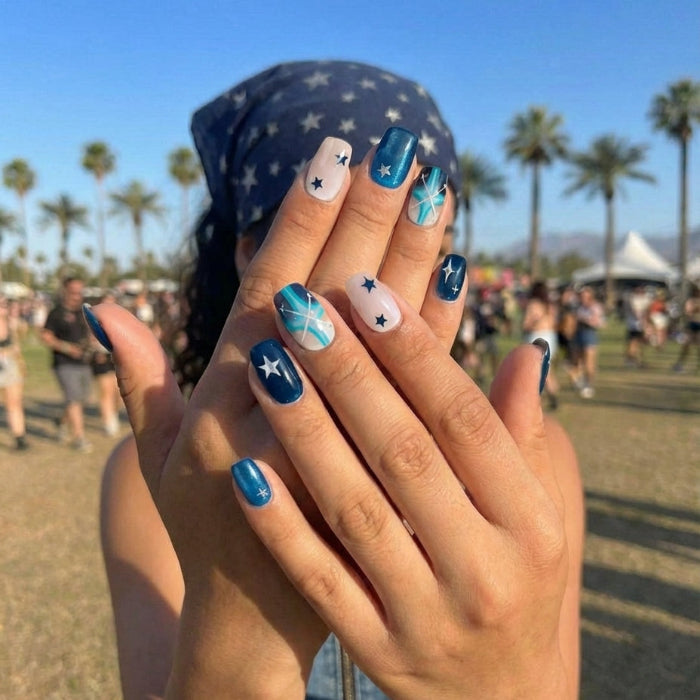 Nail art design featuring navy, teal, and nude colors with stars and cross patterns.