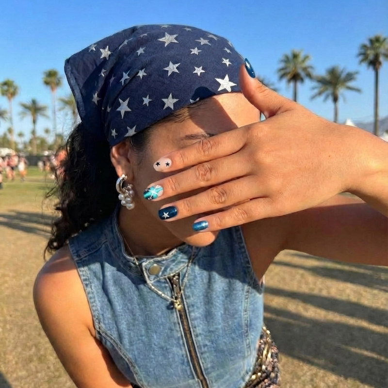 Nail art design featuring navy, teal, and nude colors with stars and cross patterns.