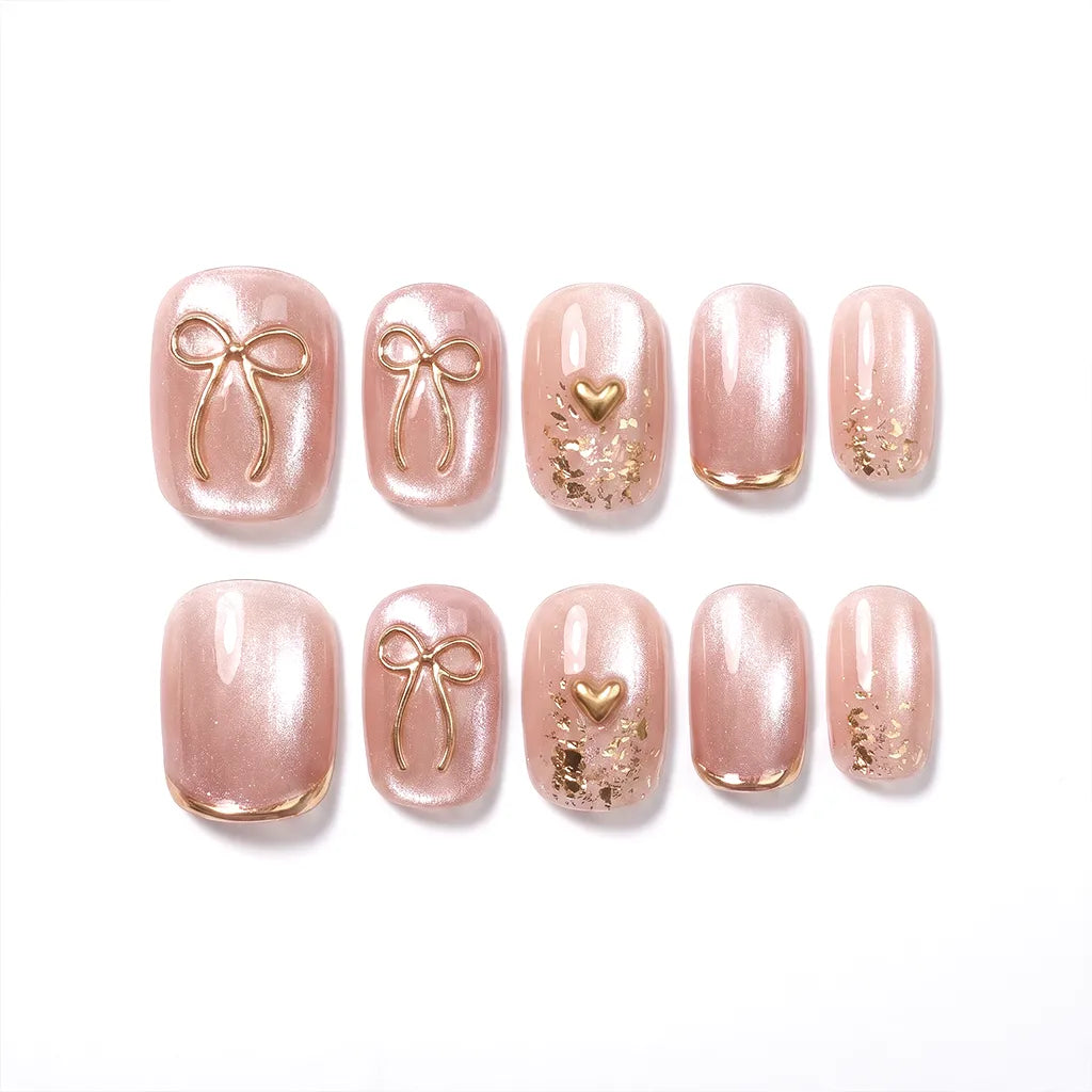 Quiet Luxe Bow press-on nails - short squoval with pearl-pink cat-eye shimmer and gold 3D bow charms