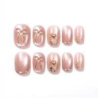 Quiet Luxe Bow press-on nails - short squoval with pearl-pink cat-eye shimmer and gold 3D bow charms