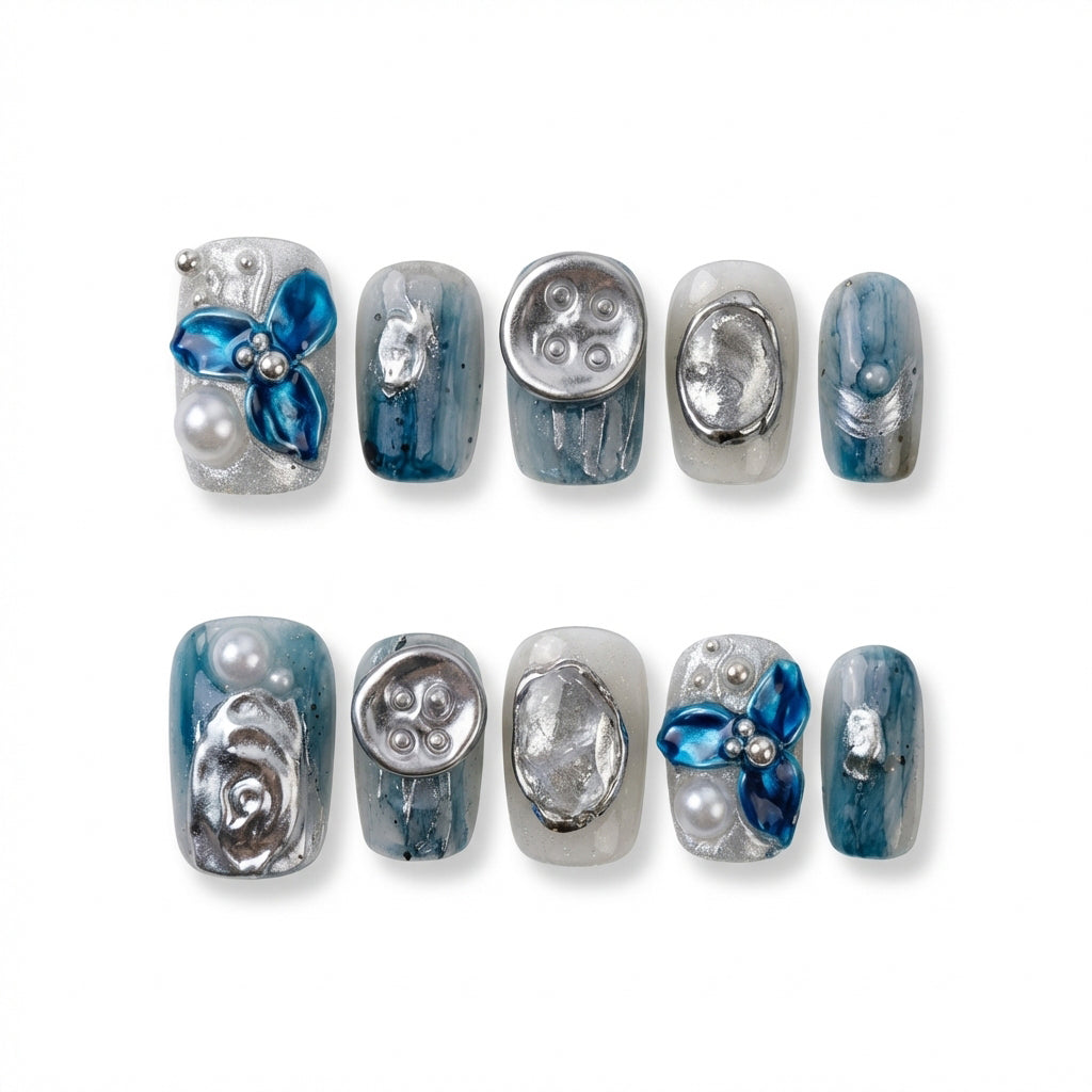 short square nail art design with blue and silver decorations, featuring flowers, pearls, and shiny elements.
