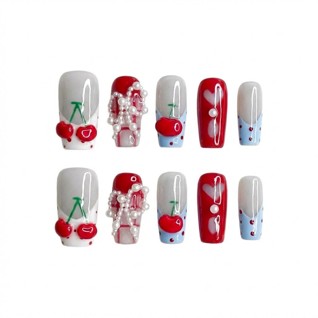 Nail art with a cherry theme featuring red, blue, and white designs with pearls