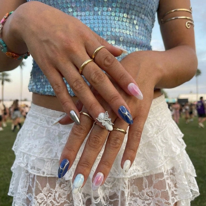 Ten decorative almond nail designs in various colors, featuring gems, a butterfly, and shiny accents.
