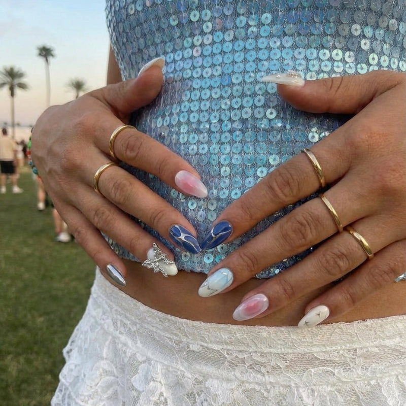Ten decorative almond nail designs in various colors, featuring gems, a butterfly, and shiny accents.