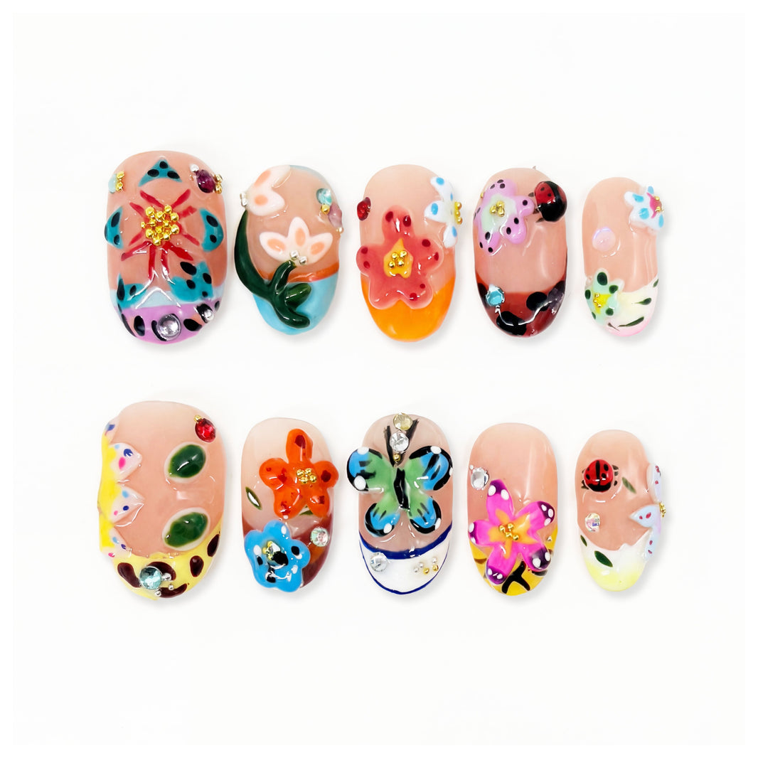 Colorful nail art set with flowers, butterflies, ladybug and gems on nude nails.