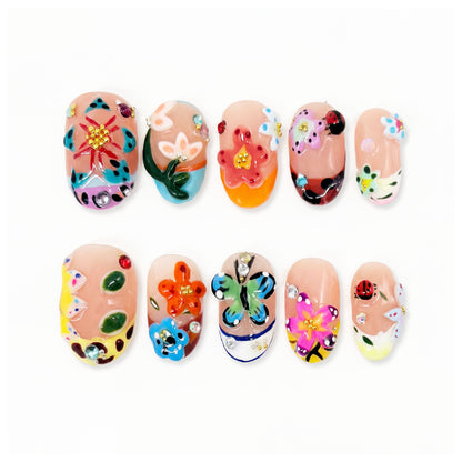 Colorful nail art set with flowers, butterflies, ladybug and gems on nude nails.